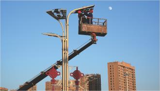 　　12月2日，工作人员在夕阳下对中心城区绿地广场路灯上的照明设施进行更换，保障了城市照明和市民夜间出行的需求。
　　
　　 本报记者
　　 杨昕 摄